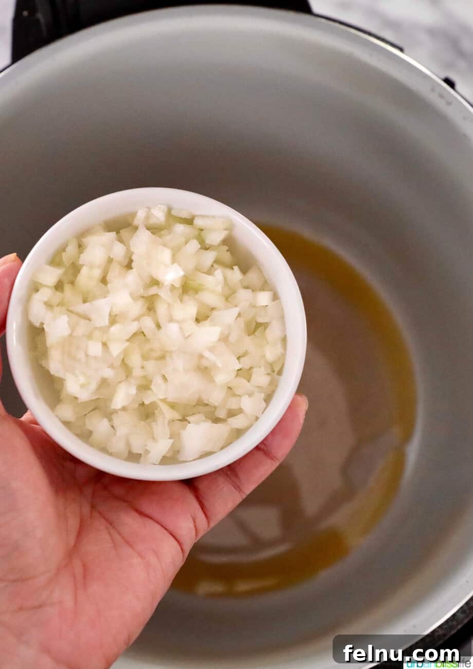Savory Butternut Instant Pot Mac and Cheese 4 Adding diced onions to the pressure cooker pot to sauté.
