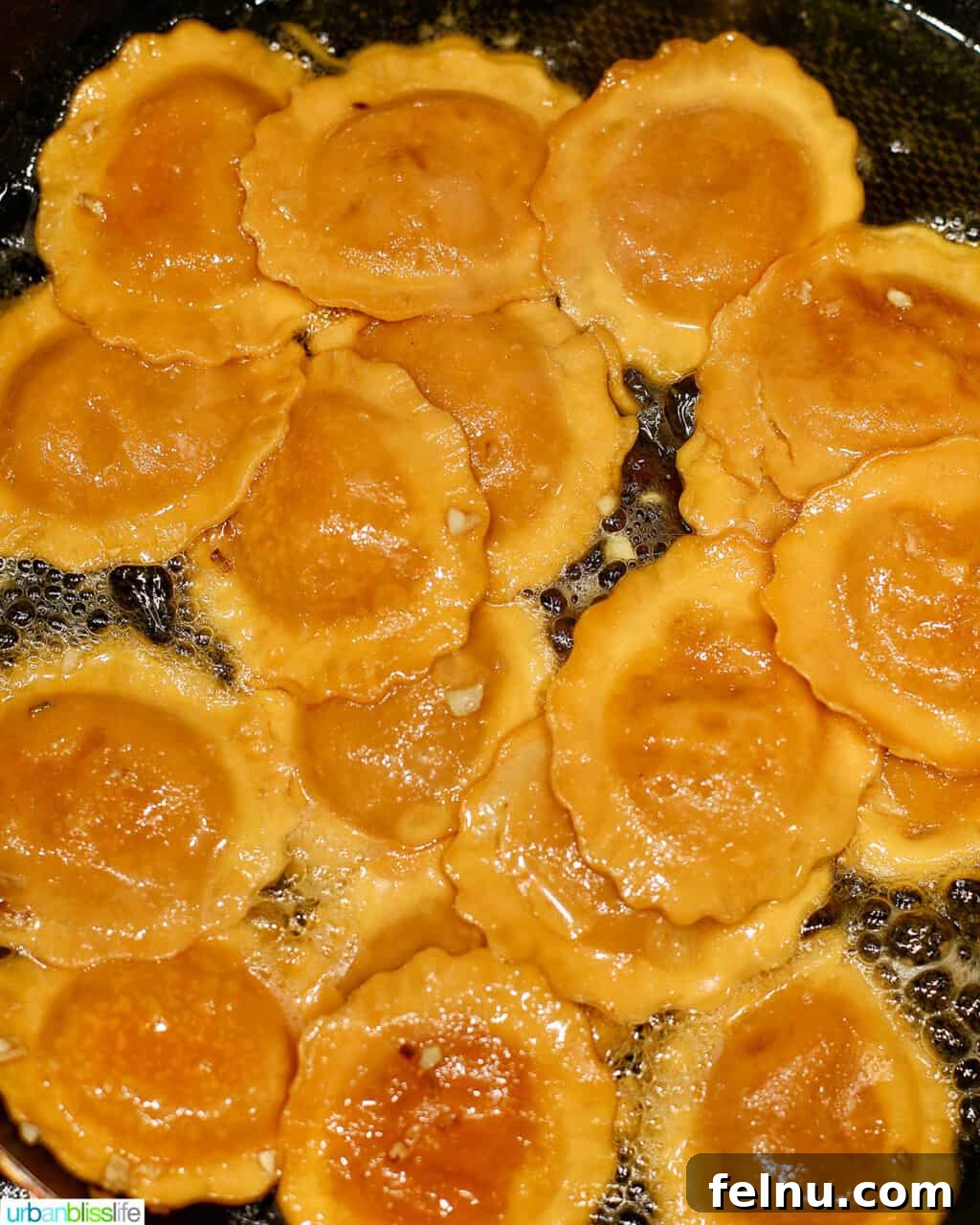 Cooked butternut squash ravioli being added to the skillet with the garlic and pecan brown butter sauce.