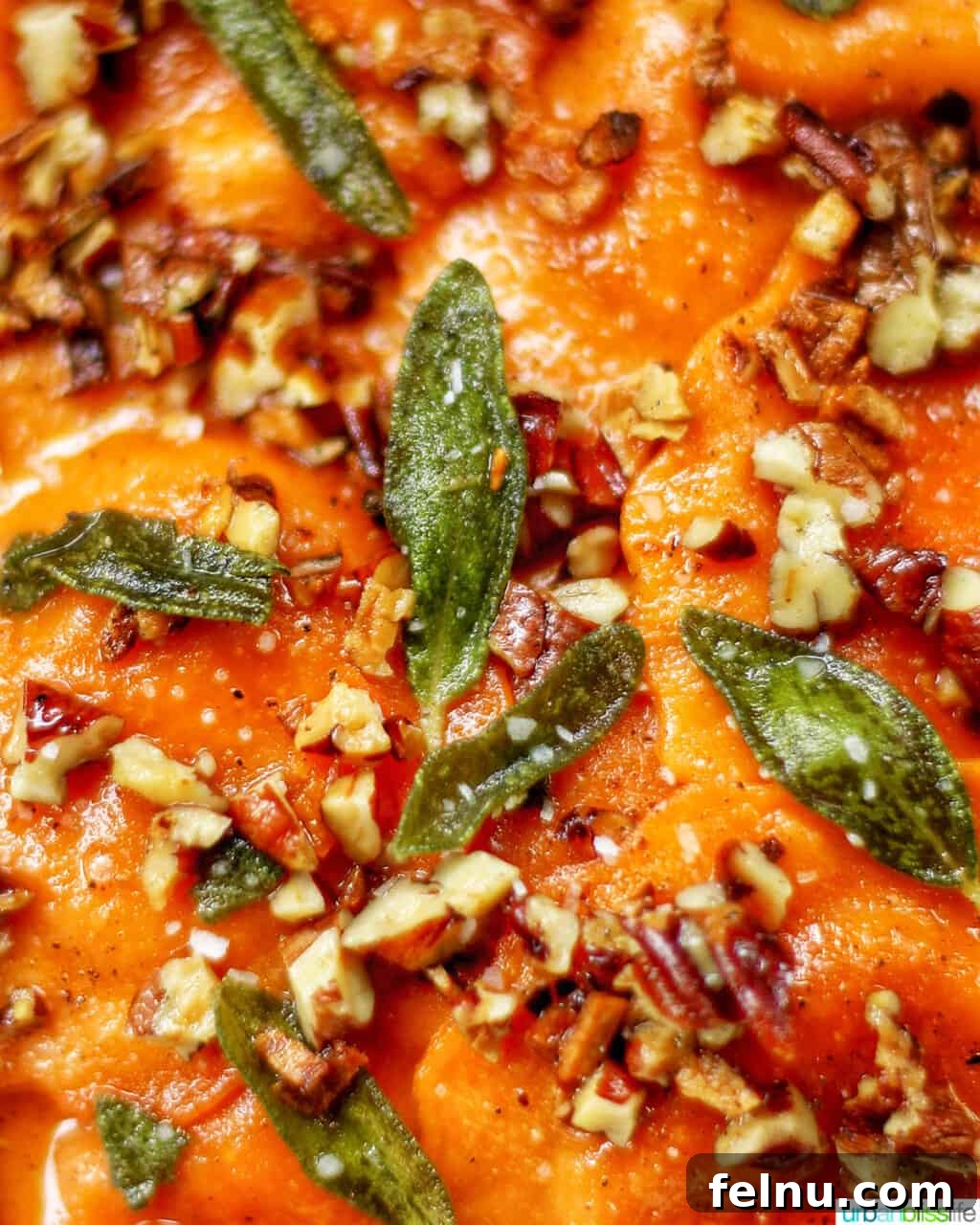 A close-up of plated butternut squash ravioli garnished with crispy sage and sautéed pecans.