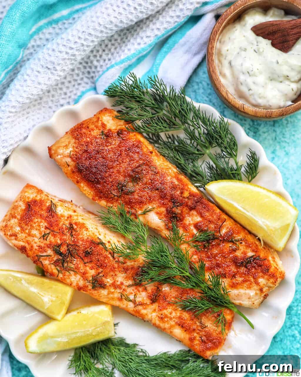 Perfect Air Fryer Salmon Every Time 15 Air fryer salmon garnished with fresh dill and served with lemon wedges and tartar sauce on a white plate.