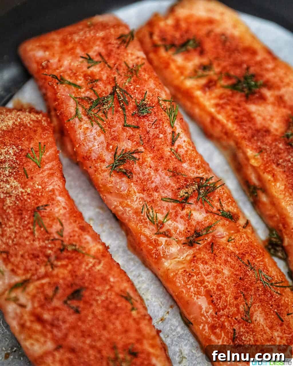 Perfect Air Fryer Salmon Every Time 3 Two perfectly cooked salmon fillets resting in an air fryer basket, showing a beautiful golden-brown crust.