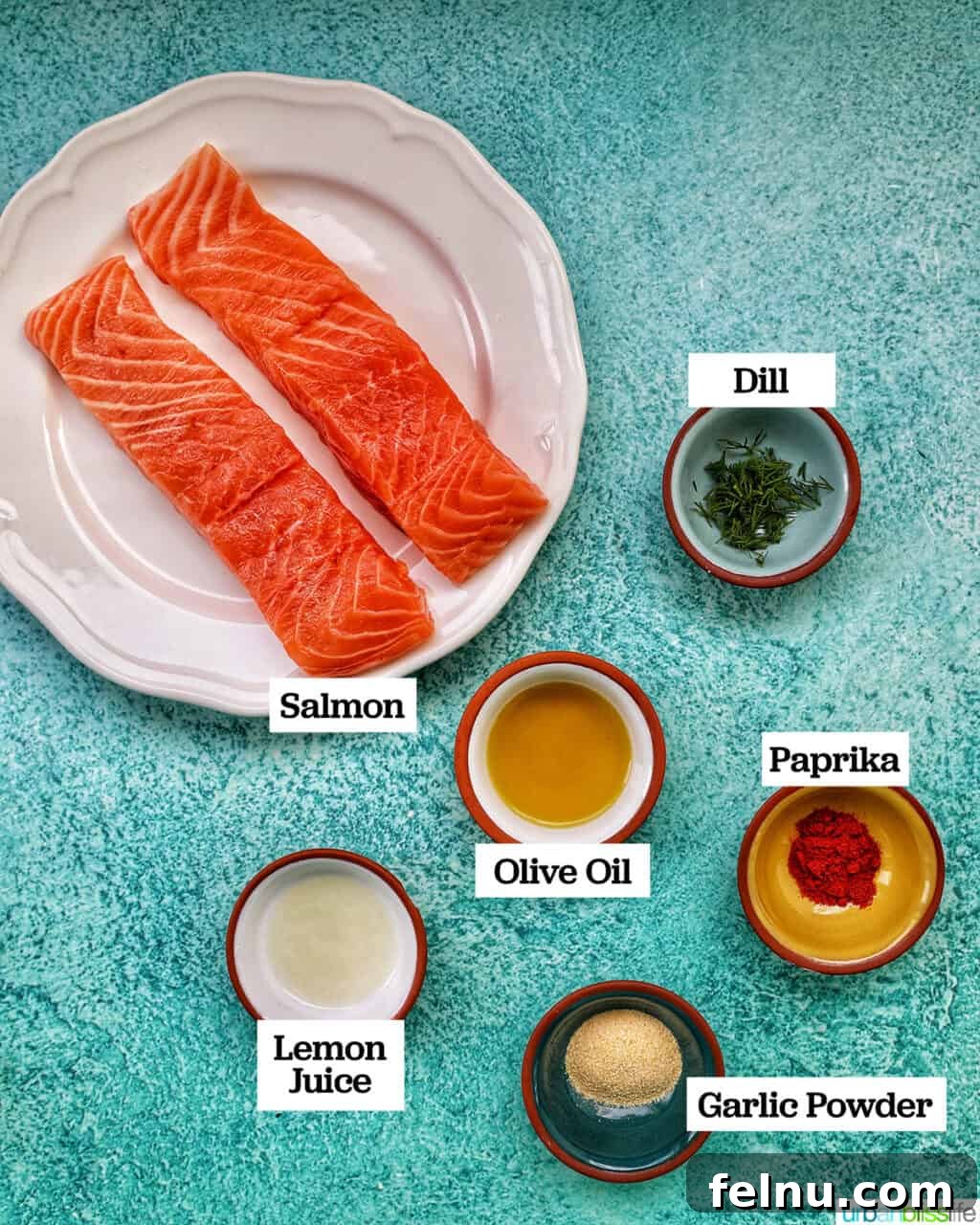Perfect Air Fryer Salmon Every Time 5 Ingredients laid out for air fryer lemon garlic paprika salmon: salmon fillets, olive oil, lemon, paprika, garlic powder, and dill.