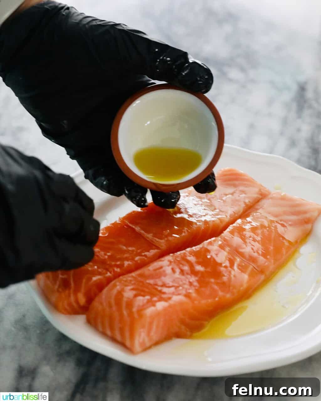 Perfect Air Fryer Salmon Every Time 8 A hand gently rubbing olive oil onto a raw salmon fillet.