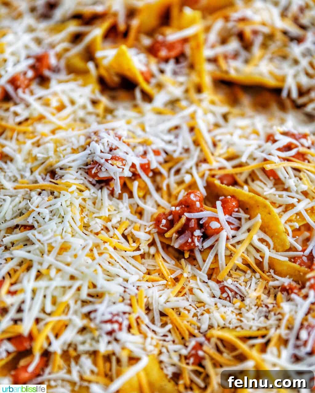 One-Pan Veggie Tex-Mex Nacho Fiesta 9 Close up view of cheese being added to beans and chips for vegetarian nachos