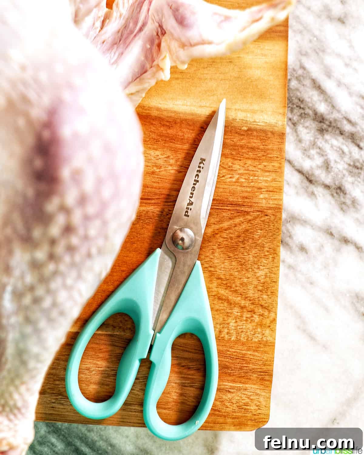 KitchenAid kitchen shears used to spatchcock a turkey on a cutting board.
