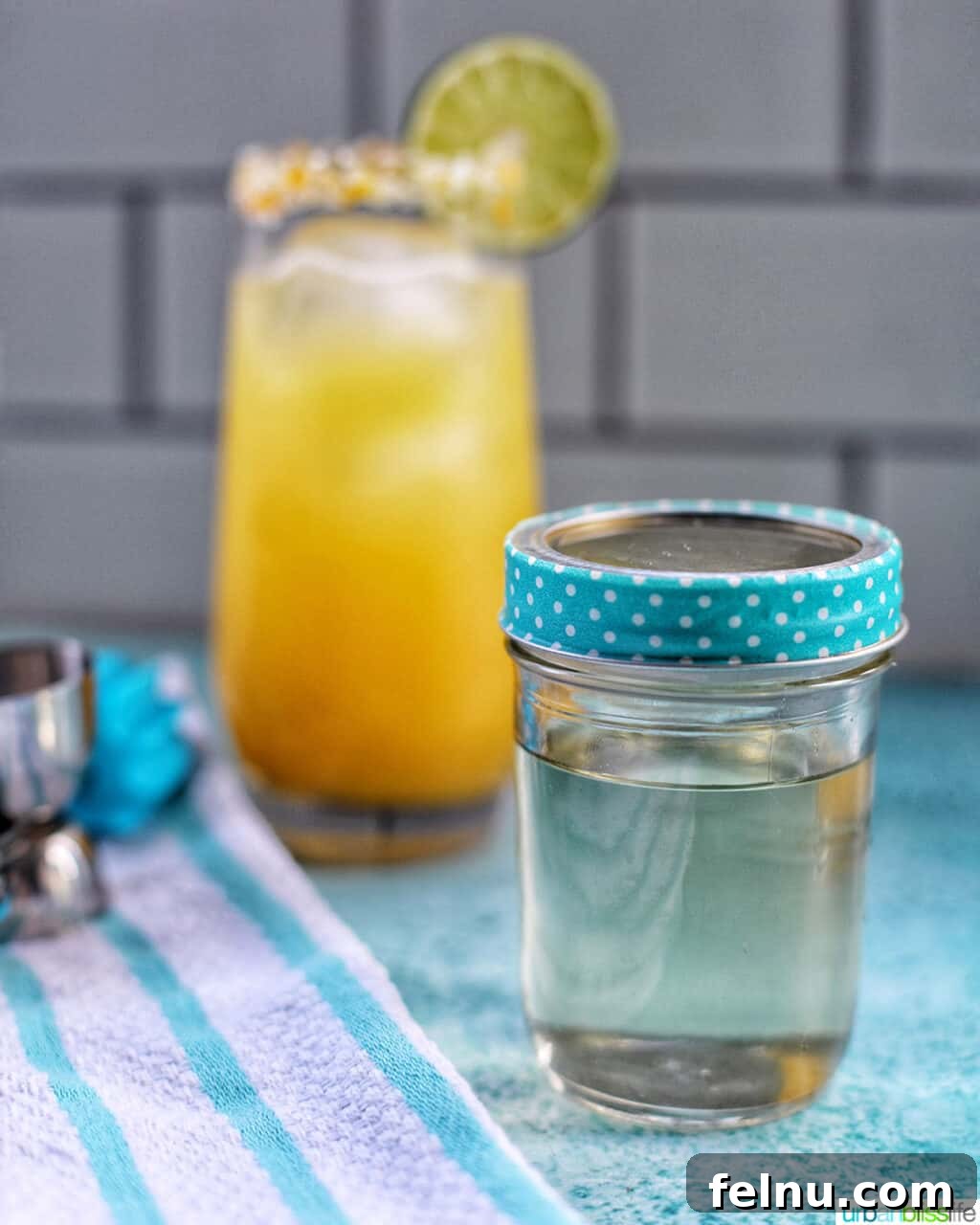 Effortless Simple Syrup: Sweeten Anything 2 A glass jar filled with golden simple syrup, with a refreshing cocktail blurred in the background, hinting at its many uses.