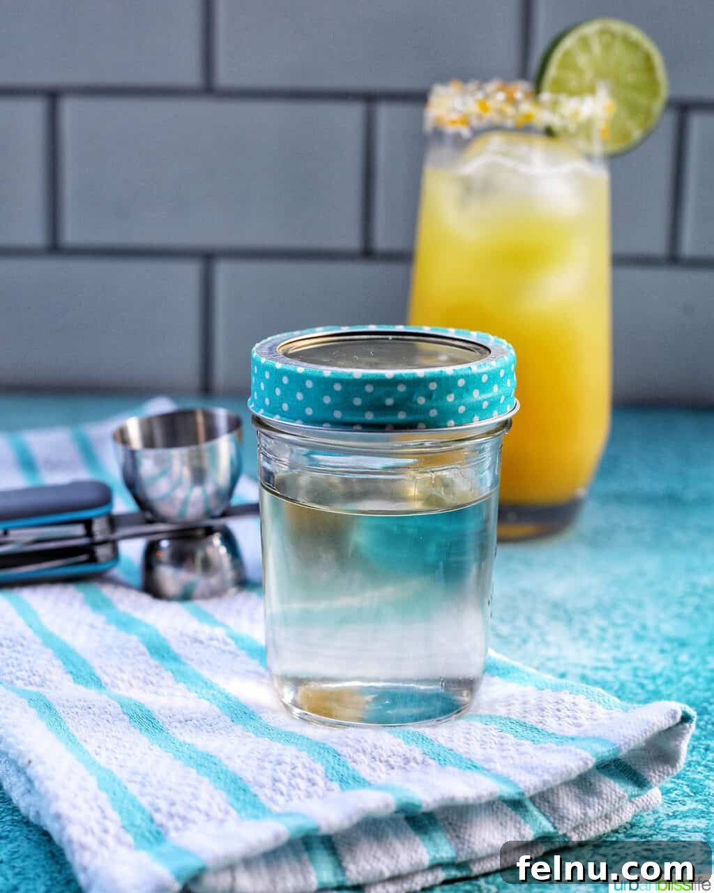Effortless Simple Syrup: Sweeten Anything 3 A glass jar of homemade simple syrup, with a fresh cocktail in the background, showcasing its primary uses.