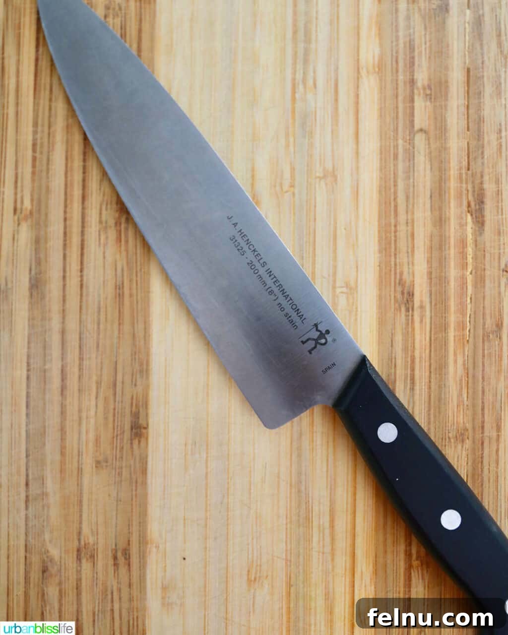 Sharpen Your Skills: The Definitive Guide to Kitchen Knives 3 A high-quality Henckels chef's knife resting on a rustic wooden cutting board, ready for use.