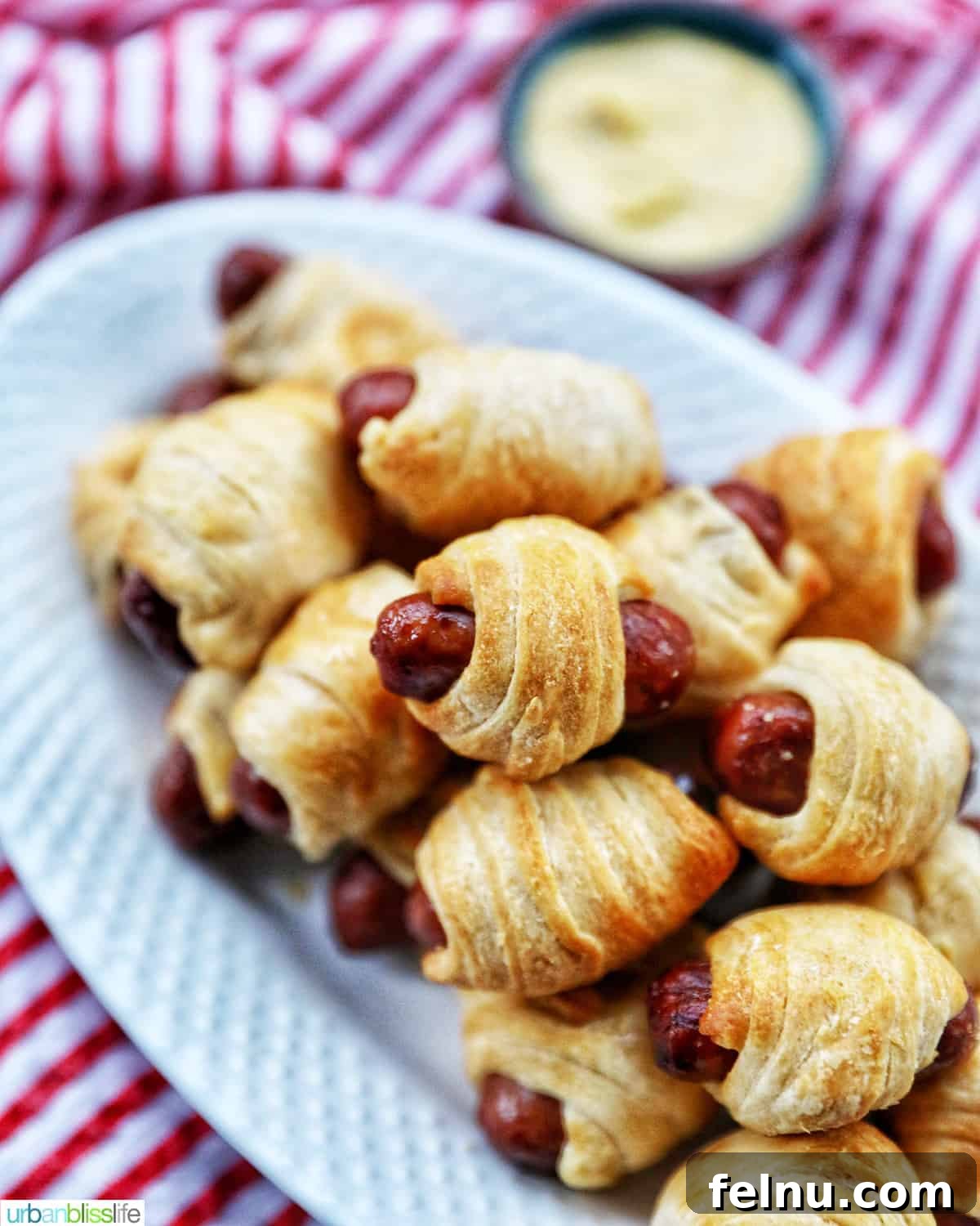 Crispy Air-Fried Pigs in a Blanket 12 dozens of Air Fryer Pigs in a Blanket stacked on top of a white plate.
