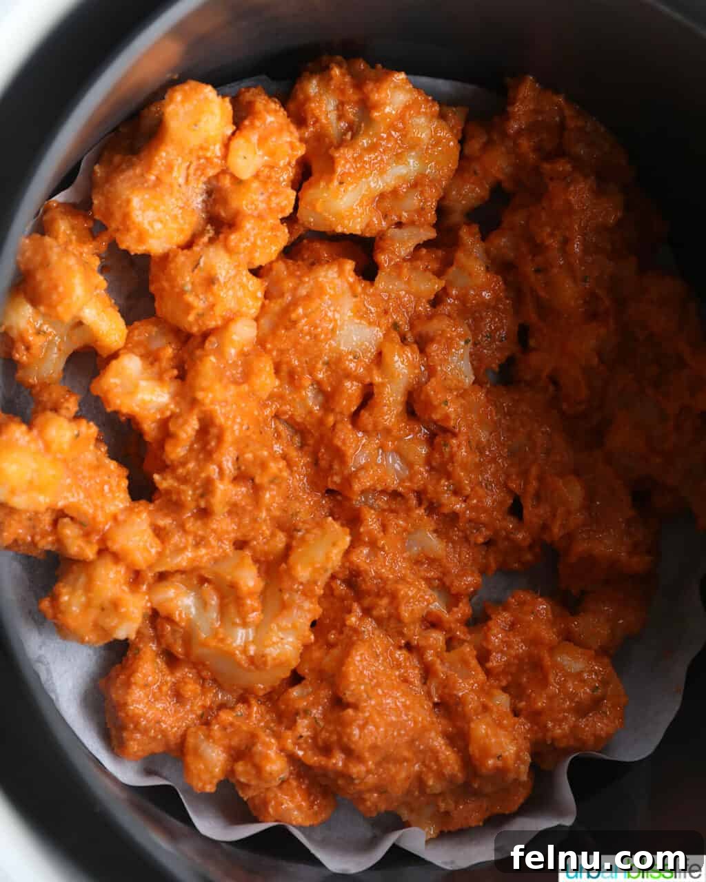 Fiery Air-Fried Cauliflower Poppers 11 Buffalo cauliflower arranged in an air fryer basket lined with parchment paper.