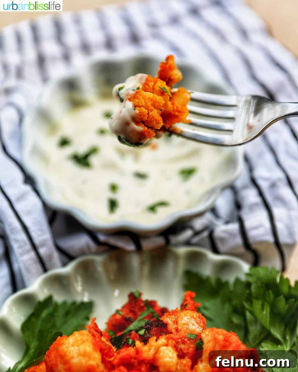 Fiery Air-Fried Cauliflower Poppers 13 A fork holding a piece of crispy air fryer buffalo cauliflower, showing its cooked texture.