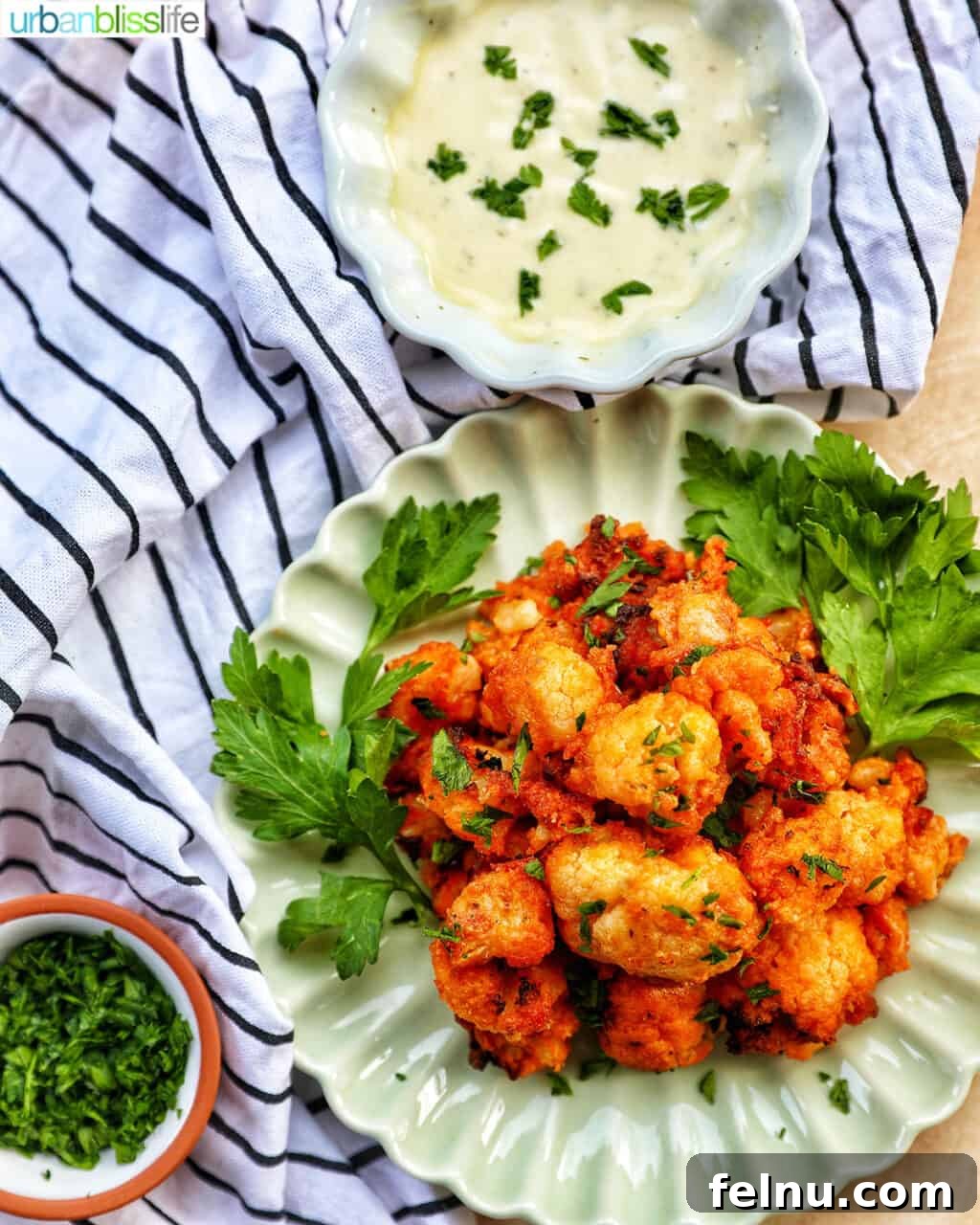 Fiery Air-Fried Cauliflower Poppers 14 Crispy air fryer buffalo cauliflower served with a side of dipping sauce and fresh parsley garnish.