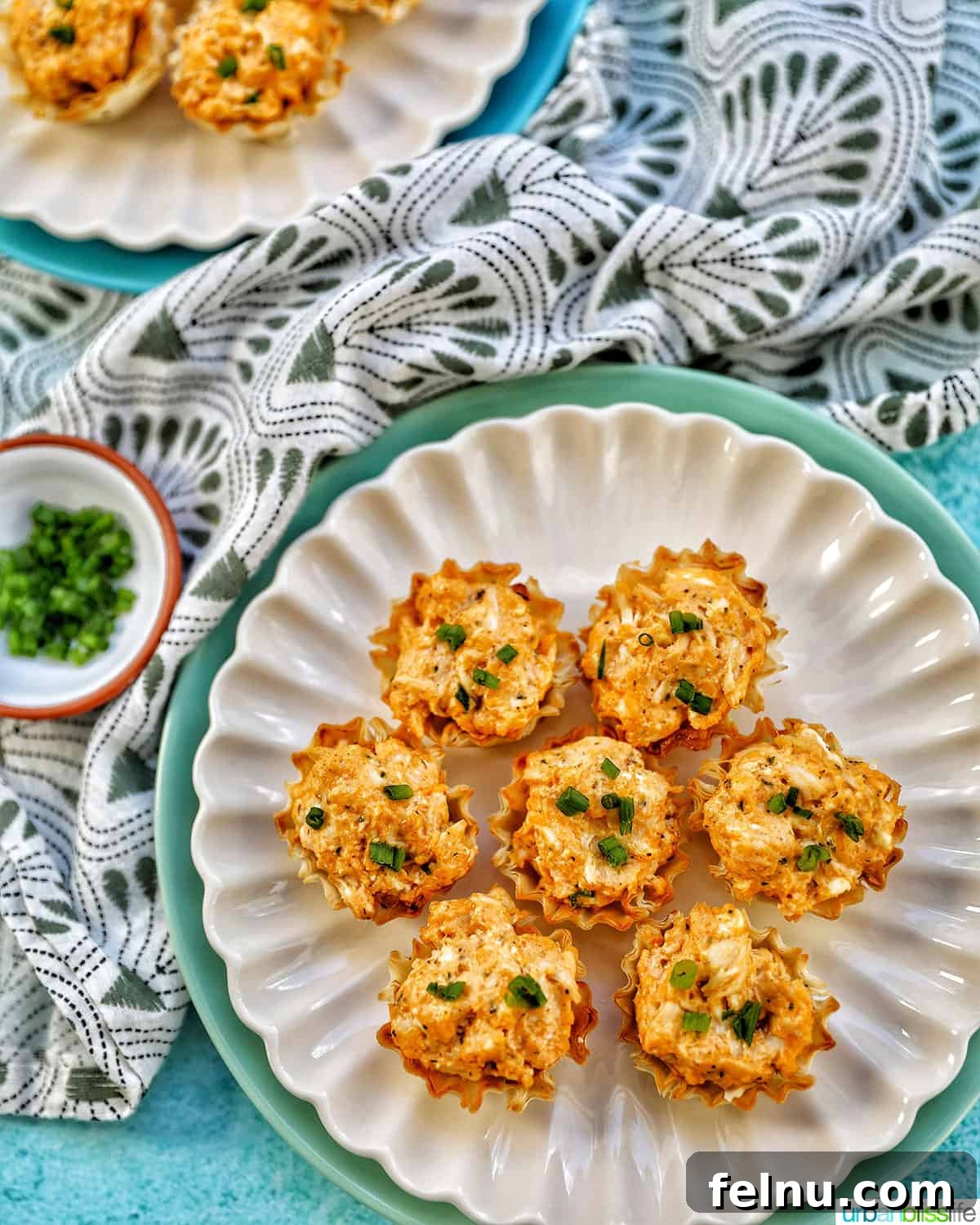 Kickin' Chicken Poppers 15 Several Buffalo Chicken Bites with chopped green onions on plates, accompanied by a green and white napkin.