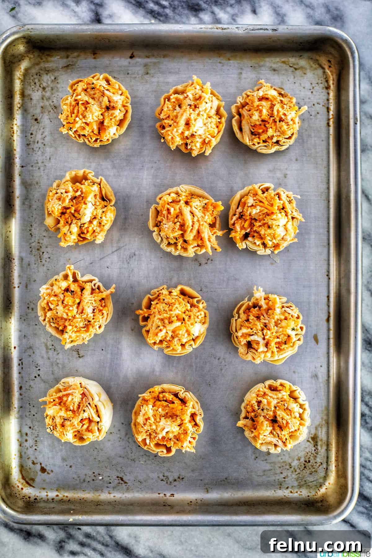 Spicy Buffalo Chicken Poppers 16 A dozen buffalo chicken bites neatly arranged on a sheet pan, ready for the oven, showcasing the simplicity of the setup.