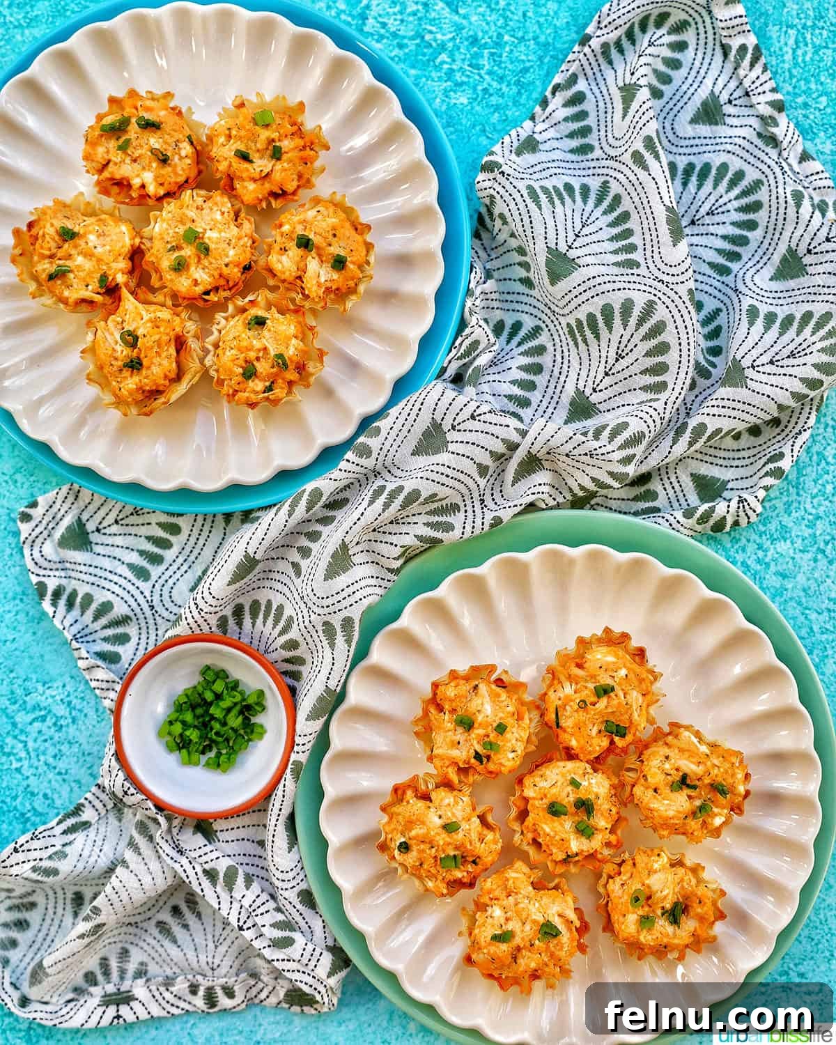 Spicy Buffalo Chicken Poppers 17 Several buffalo chicken bites presented on two separate plates, accompanied by a small bowl of chopped green onions and a green and white napkin.