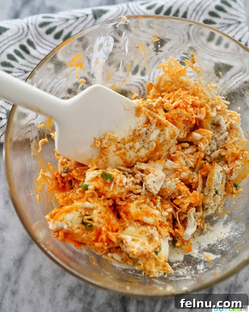 Spicy Buffalo Chicken Poppers 9 A spoon mixing the buffalo chicken filling in a bowl, showcasing its readiness.