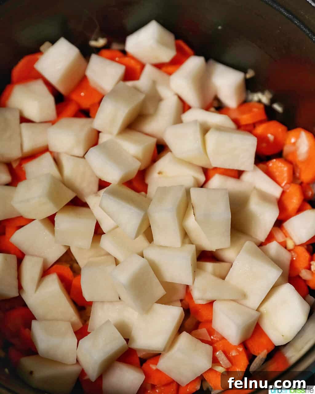 Adding potatoes to carrots.