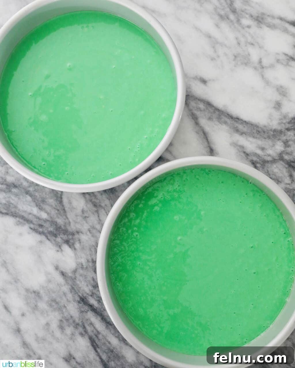 Emerald Velvet Delight with Tangy Cream Cheese 18 Two cake pans filled evenly with green cake batter, ready for baking.