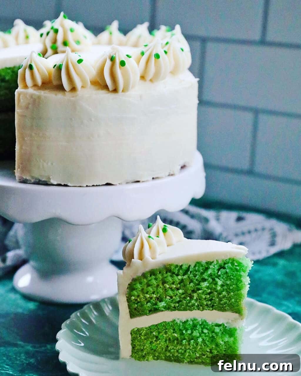 Emerald Velvet Delight with Tangy Cream Cheese 3 A slice of green velvet cake on a plate, showcasing its soft crumb and thick cream cheese frosting.