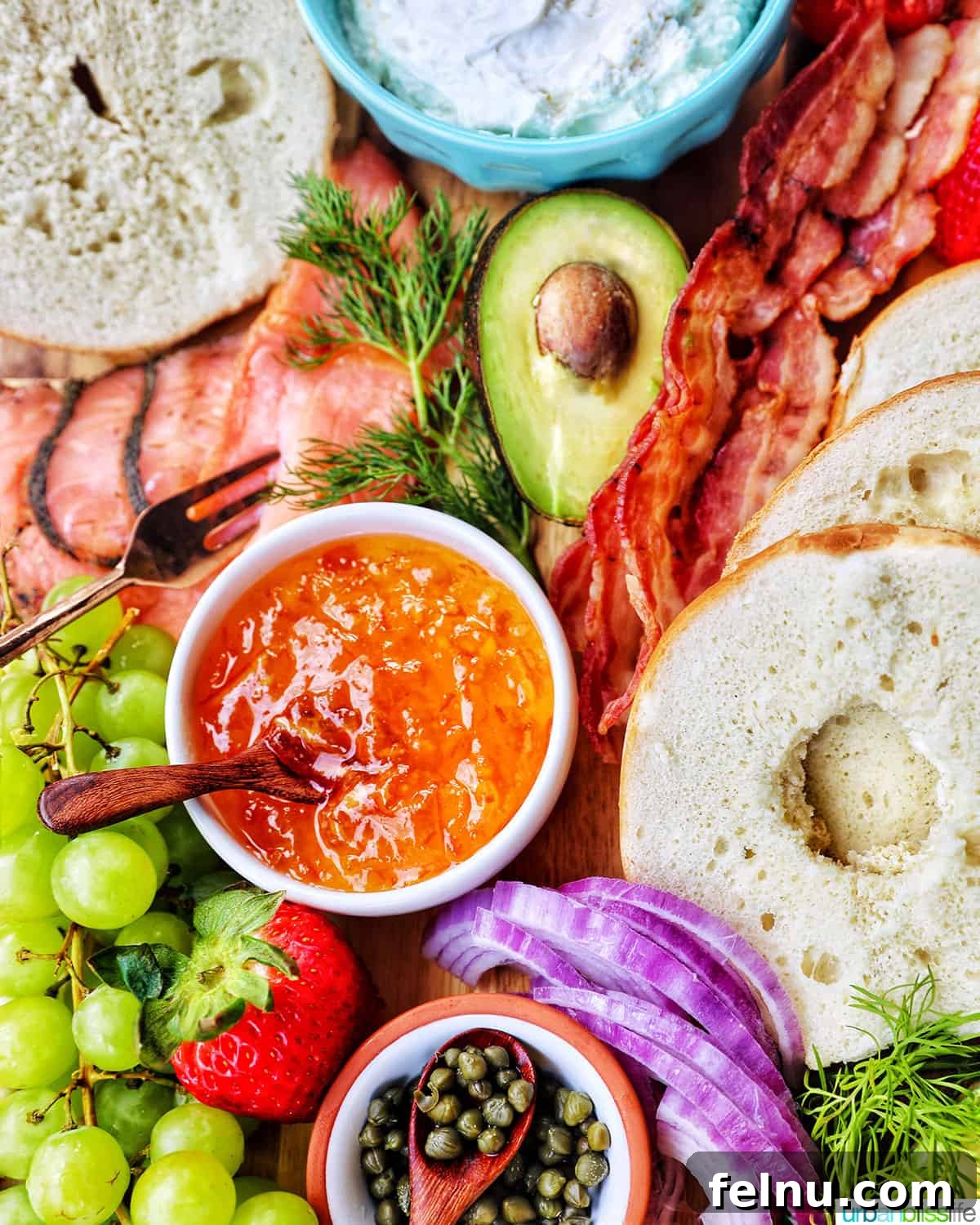 Brunch Grazing Platter 5 A beautifully arranged brunch board featuring orange marmalade surrounded by an array of fruits, vegetables, bagels, and bacon.