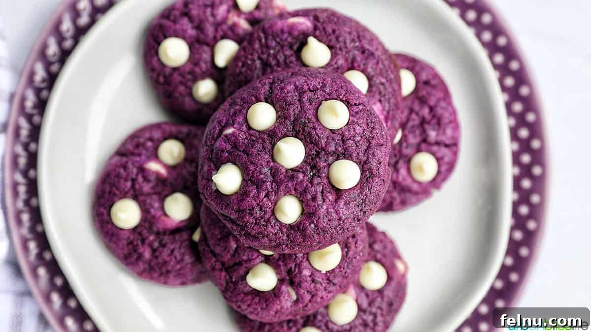 Ube and White Chocolate Dream Cookies 20 stacks of bright purple Ube cookies with white chocolate chips on a white and purple plate.