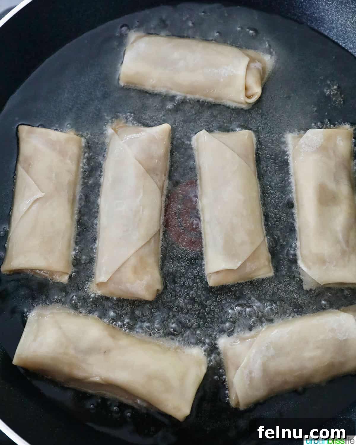 Effortless Filipino Turon: Crispy Banana Lumpia Perfection 17 Frying Filipino turon banana lumpia in a pan.