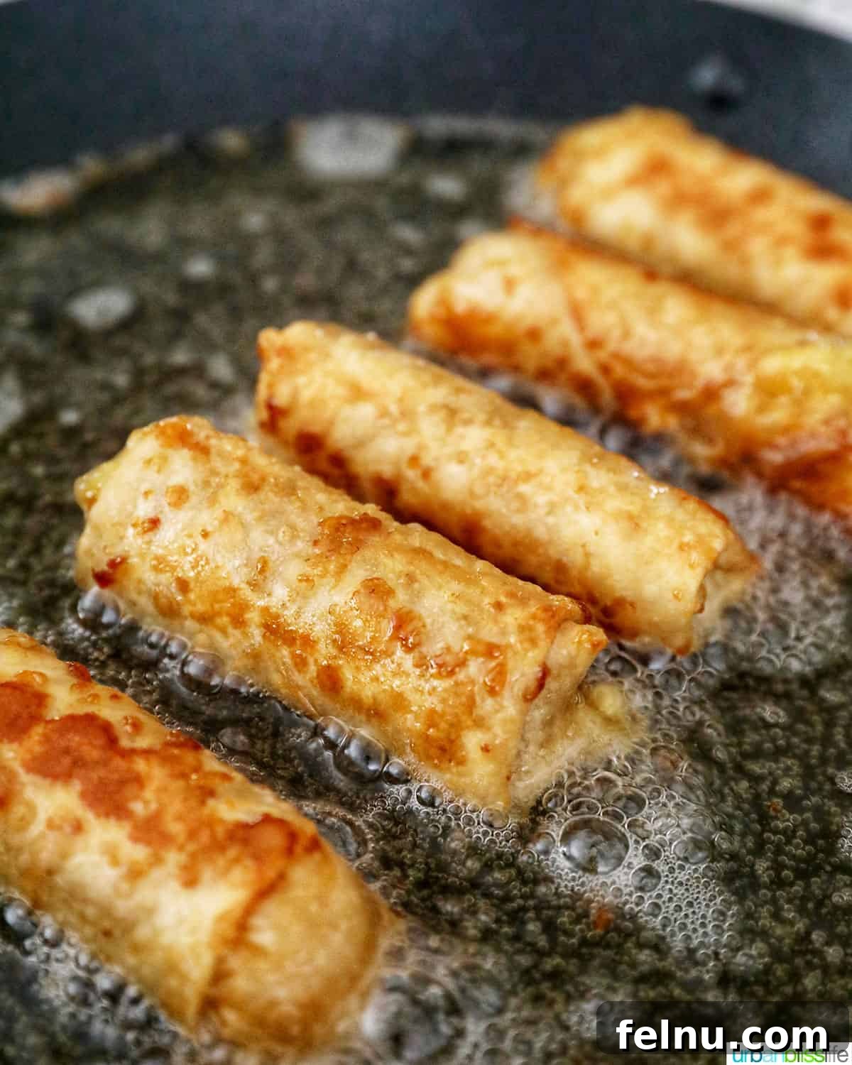 Effortless Filipino Turon: Crispy Banana Lumpia Perfection 18 Filipino turon banana lumpia frying in a pan, golden brown.