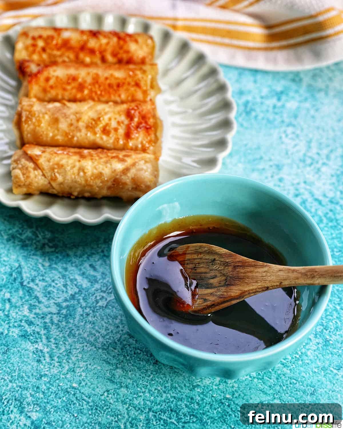 Effortless Filipino Turon: Crispy Banana Lumpia Perfection 21 Caramel drizzle in a bowl next to plate of Filipino turon banana lumpia.