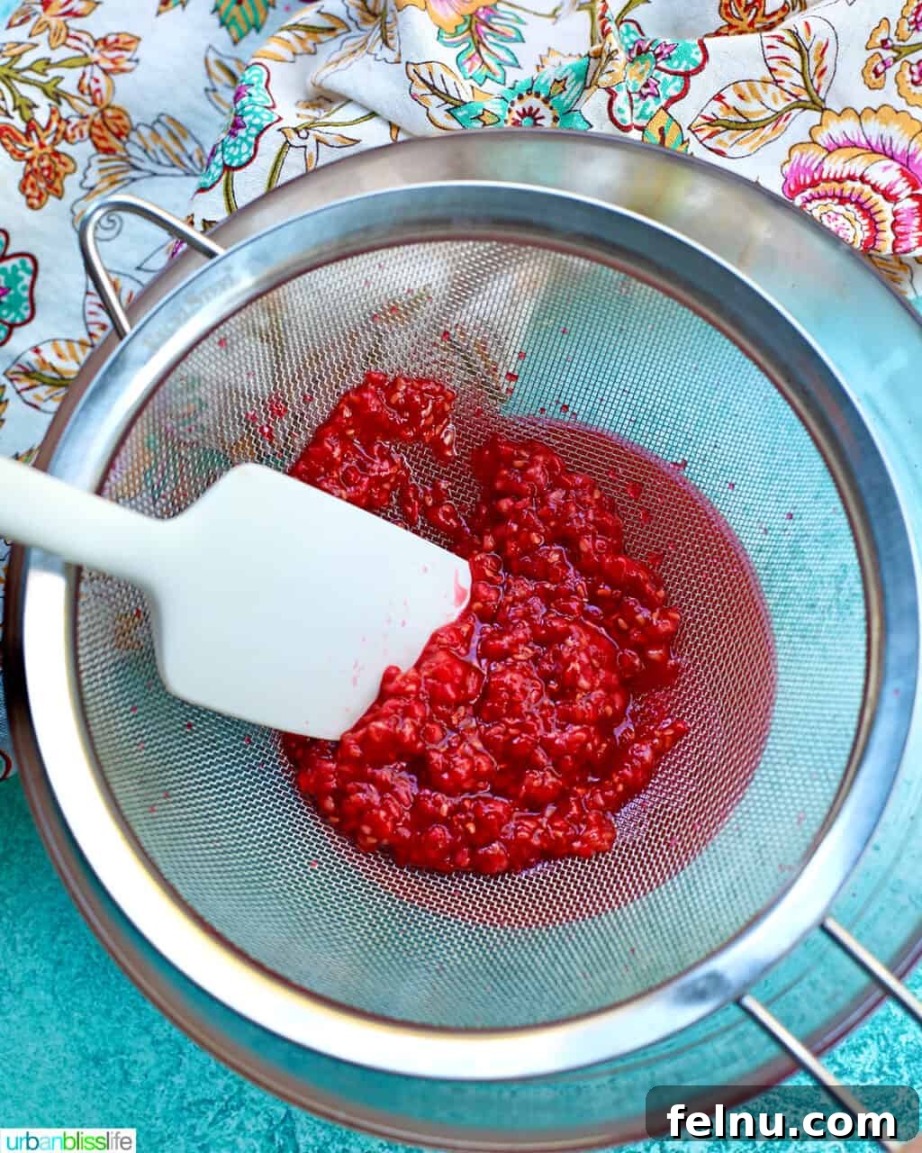Raspberry Sparklers 12 Straining the raspberry puree through a fine-mesh sieve to remove seeds.