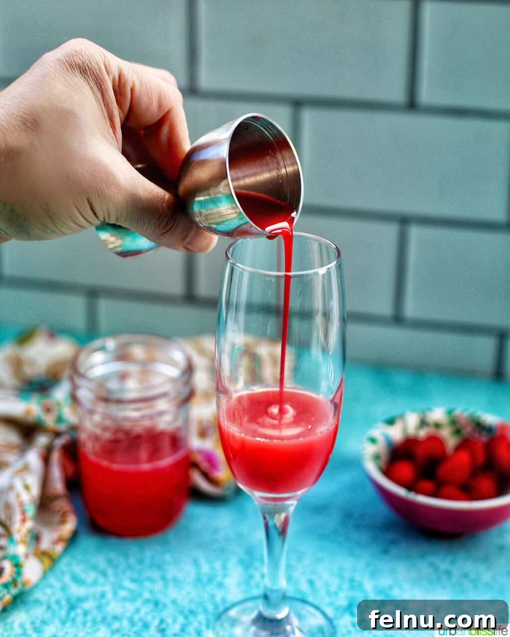 Raspberry Sparklers 15 Pouring raspberry puree into a champagne flute to prepare Raspberry Mimosas.