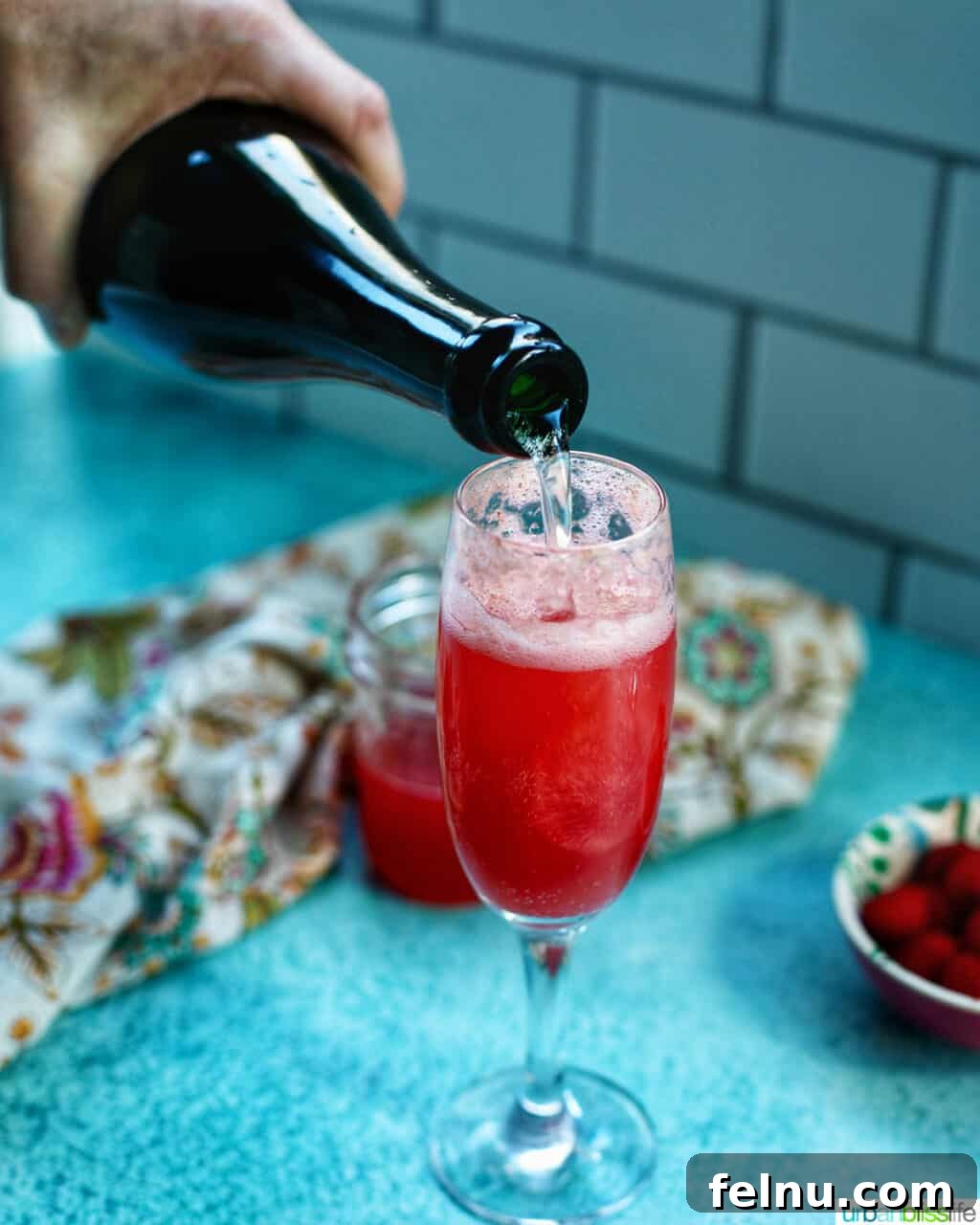 Raspberry Sparklers 16 Pouring sparkling wine into a champagne flute to make Raspberry Mimosas.