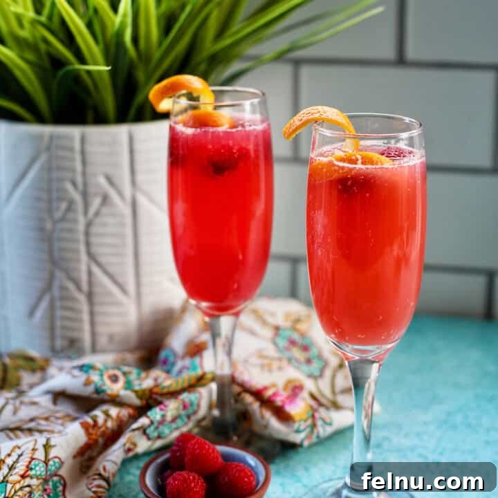 Two raspberry mimosas in champagne flutes.