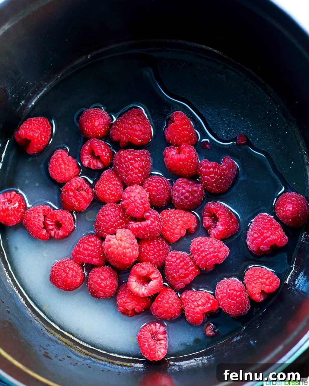Raspberry Sparklers 8 Fresh raspberries being added to the simmering simple syrup in a pot.