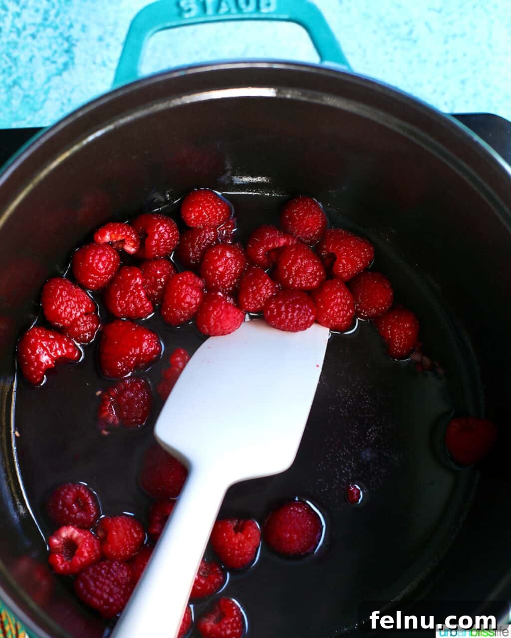 Raspberry Sparklers 9 Stirring raspberries in a pot to create a rich raspberry syrup.