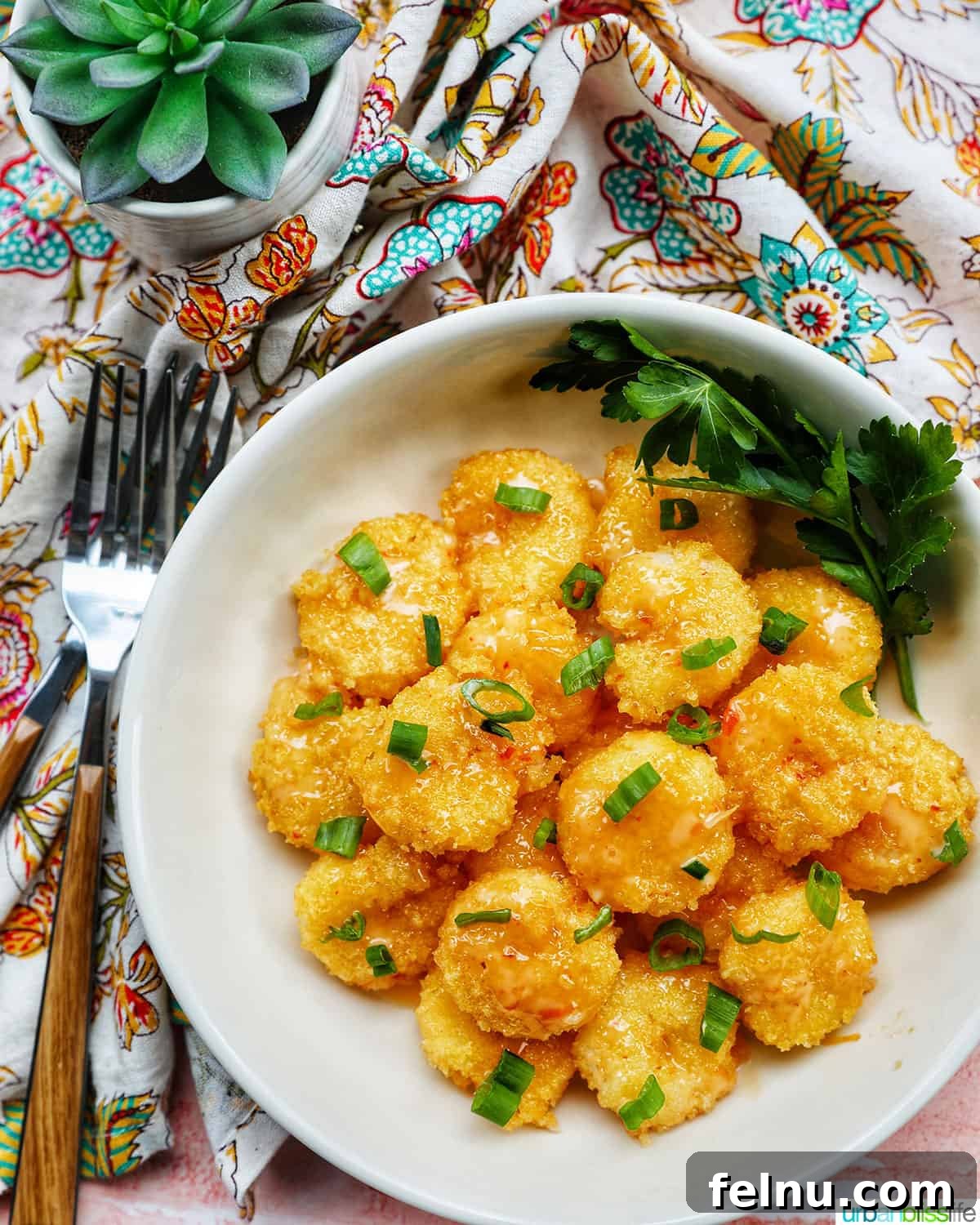 Bang Bang Shrimp: An Air Fryer Sensation 19 Air fryer bang bang shrimp garnished with green onions in a white bowl with forks and a colorful napkin.