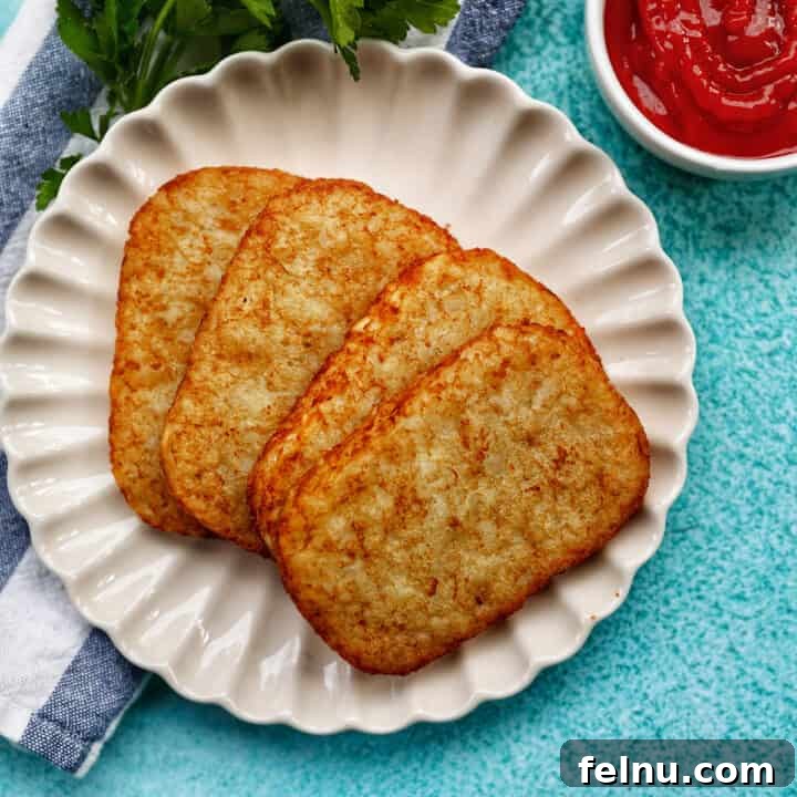 Air Fried Golden Hash Browns 11 hash brown patties on a white plate with side of ketchup, greens, and blue background.