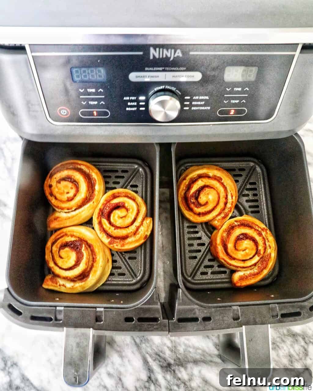 Golden Air Fryer Cinnamon Swirls 12 Finished air fried cinnamon rolls in the air fryer basket, ready to be removed