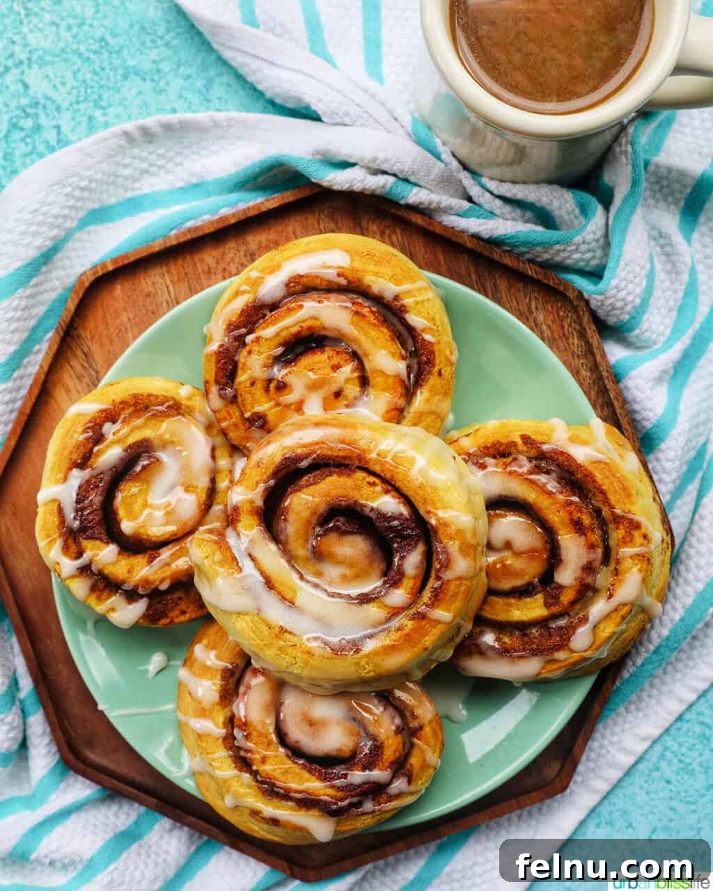 Golden Air Fryer Cinnamon Swirls 13 Air fried cinnamon rolls on a plate next to a steaming cup of coffee