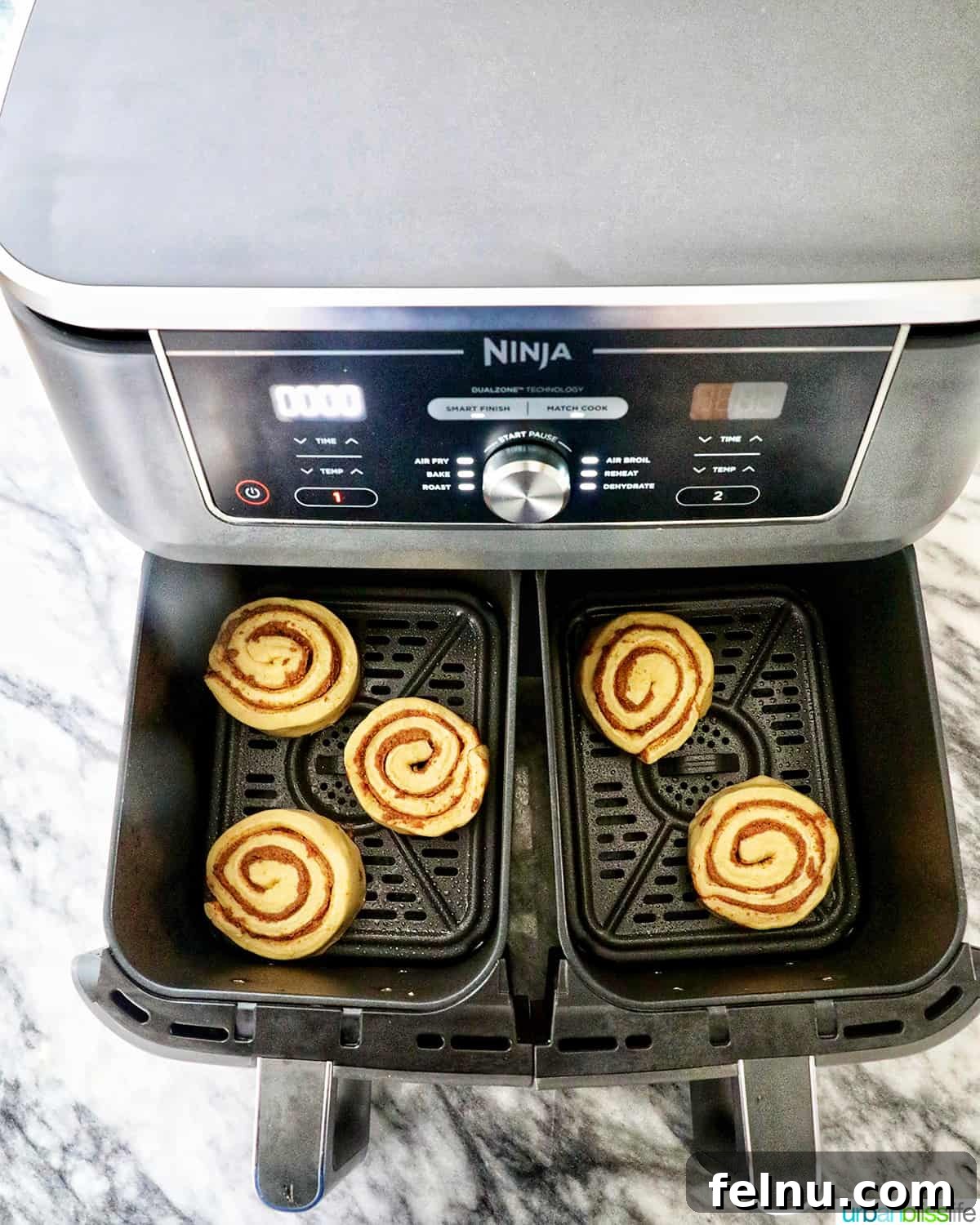 Golden Air Fryer Cinnamon Swirls 6 Uncooked cinnamon rolls arranged in the Ninja Foodi air fryer baskets