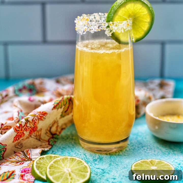 Champagne margarita in a tall glass with lime slices.