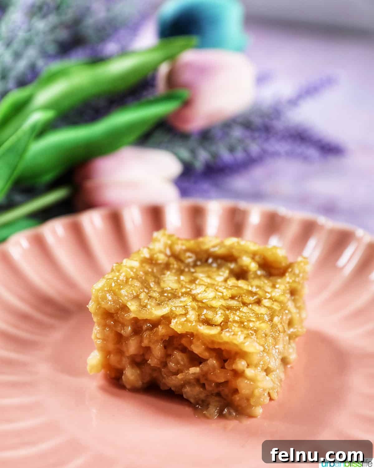 A slice of Filipino Biko on a pink scalloped plate with delicate flowers in the background.