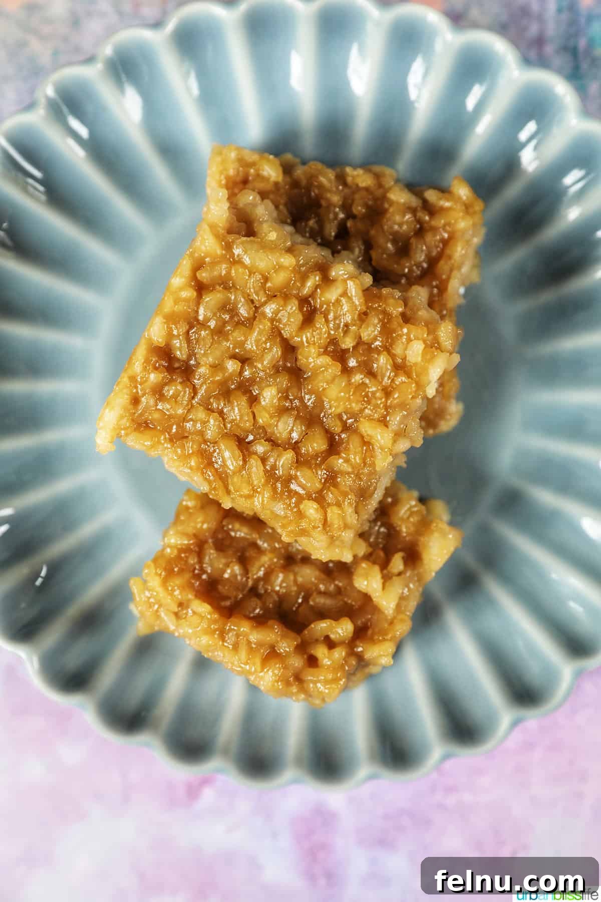 Several slices of Filipino Biko neatly stacked on a charming blue scalloped plate.
