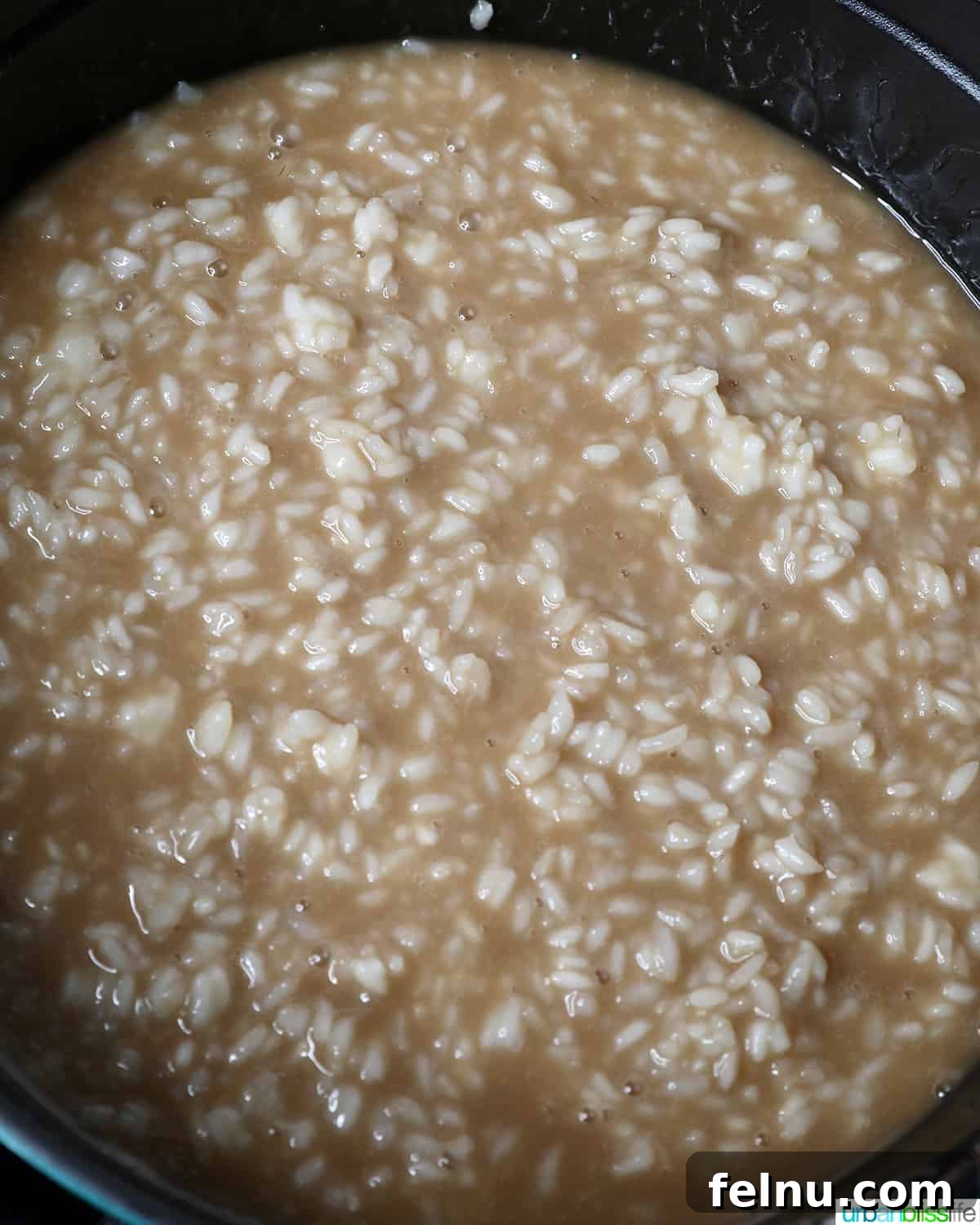 The cooked rice being stirred into the coconut milk and brown sugar mixture, creating a cohesive and flavorful base.