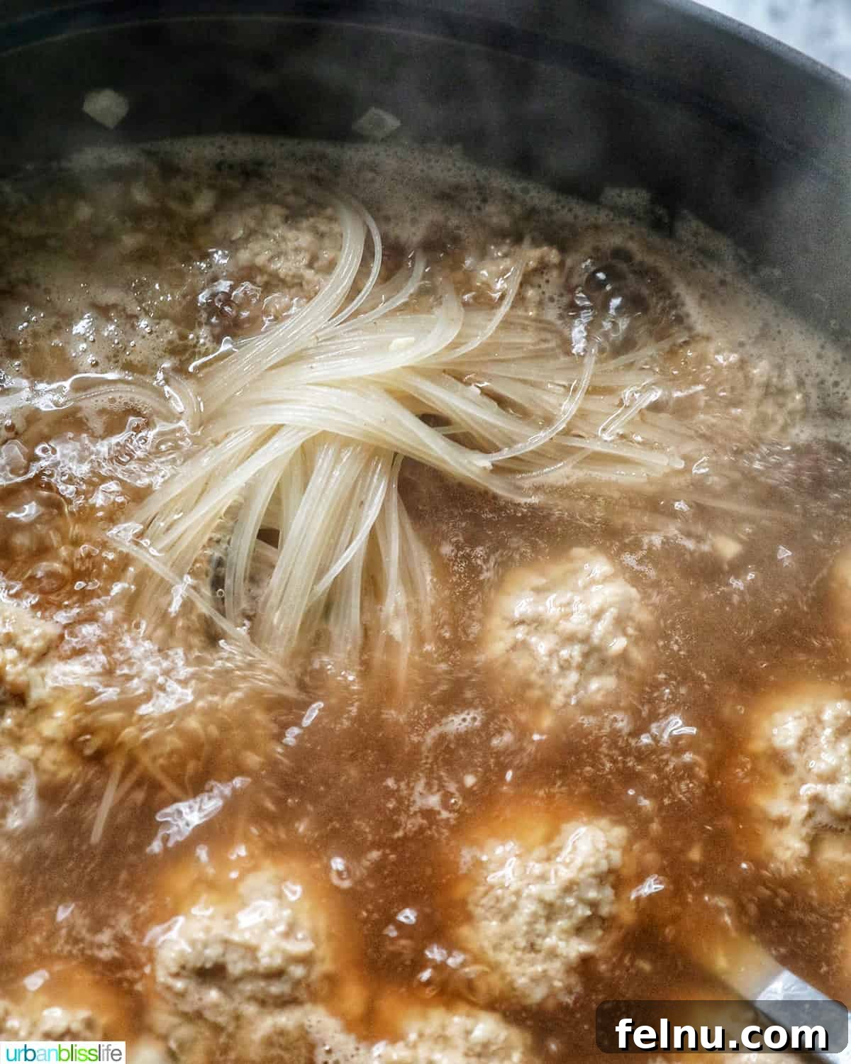 Meatballs and noodles cooking in Almondigas soup