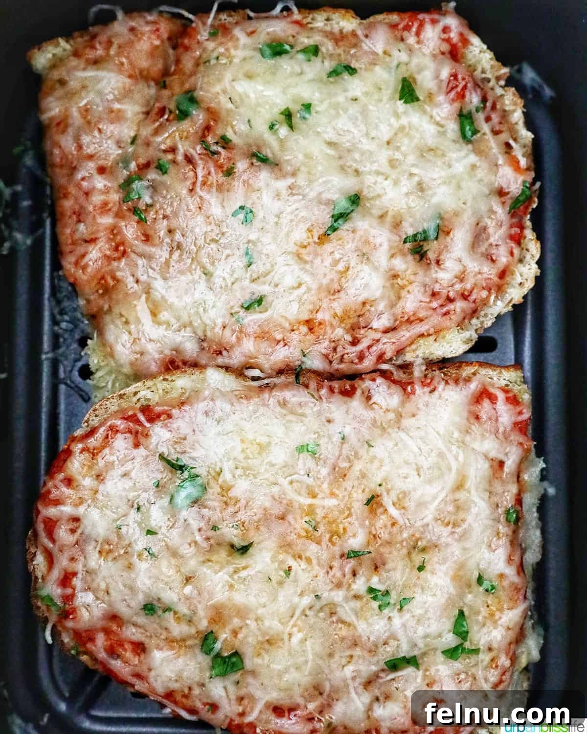 Crispy Air Fryer Pizza 12 Two perfectly cooked French bread pizzas, with melted and slightly browned cheese, still nestled in the air fryer basket.
