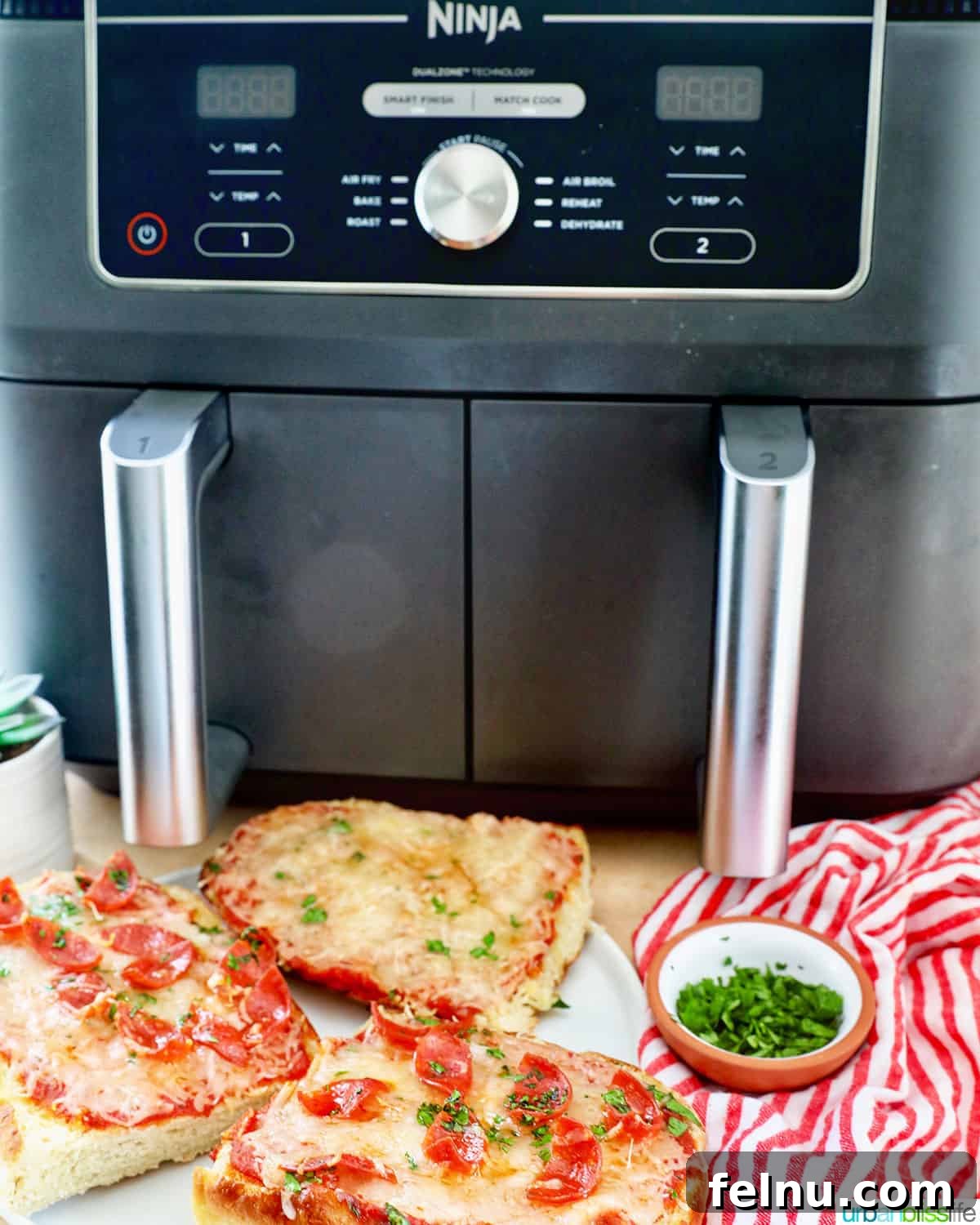 Crispy Air Fryer Pizza 14 A Ninja Foodi dual air fryer featuring a cooked French bread pizza slice, with a small bowl of fresh parsley in front, all set on a red striped napkin.