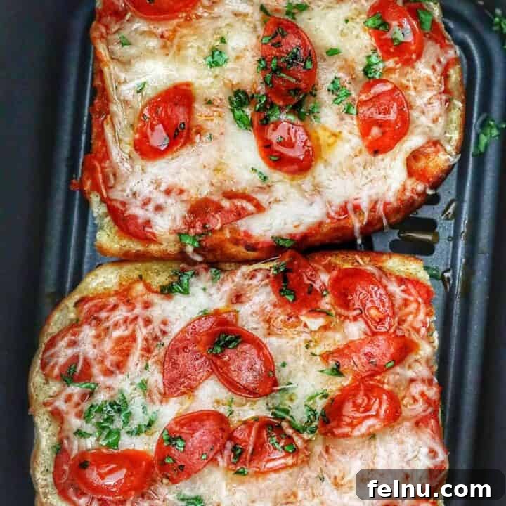 Two half loaves of french bread pizza in an air fryer basket, showing a perfectly cooked meal.