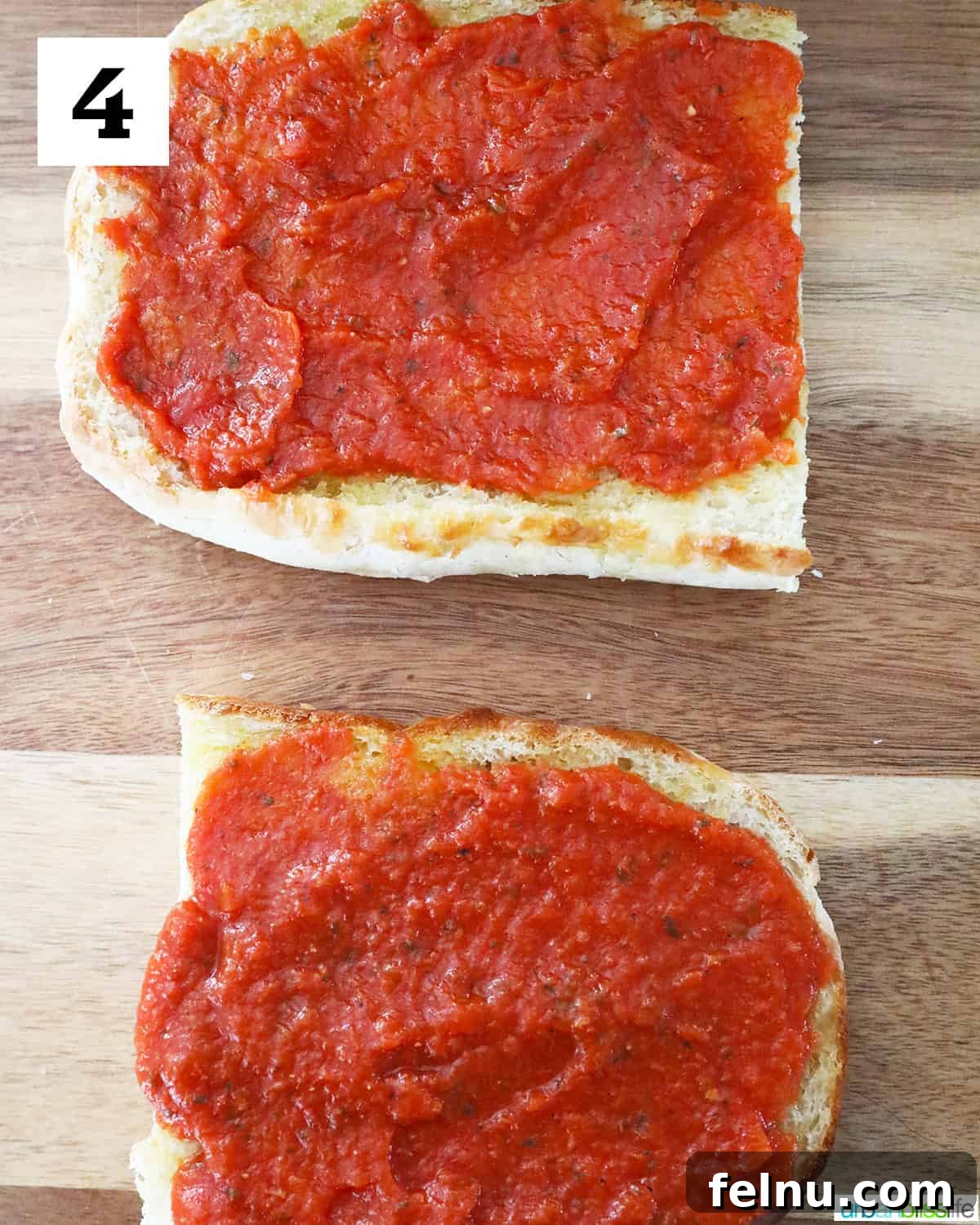 Crispy Air Fryer Pizza 8 Two halves of toasted French bread, perfectly coated with a layer of bright red pizza sauce, resting on a wooden cutting board.