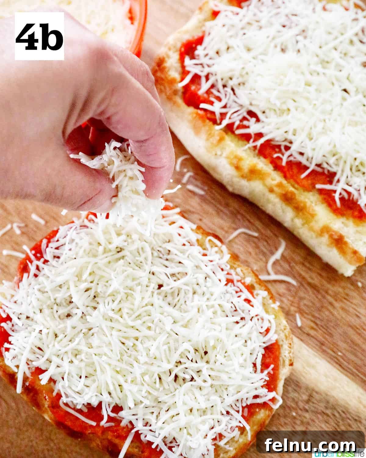 Crispy Air Fryer Pizza 9 Two halves of French bread on a cutting board, now topped with both pizza sauce and a generous layer of shredded cheese.