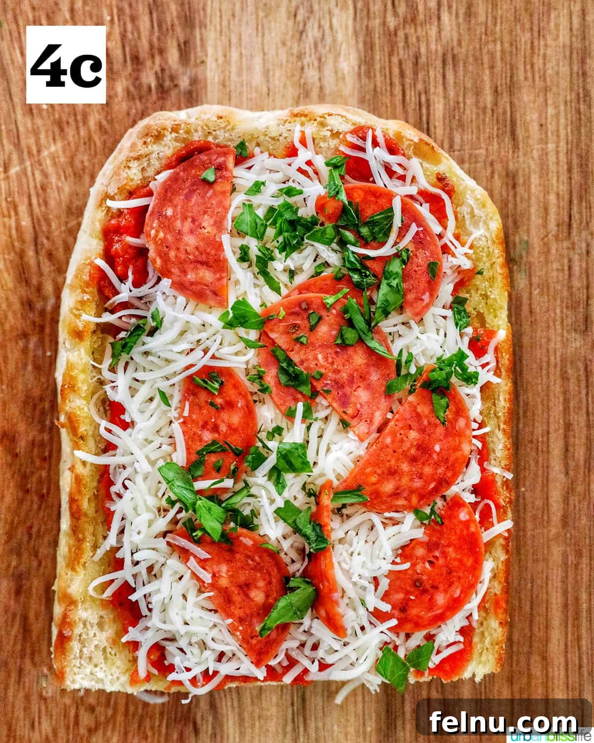 Crispy Air Fryer Pizza 10 One half of French bread, fully assembled with pizza sauce, cheese, and a sprinkle of fresh parsley, ready to be air fried.